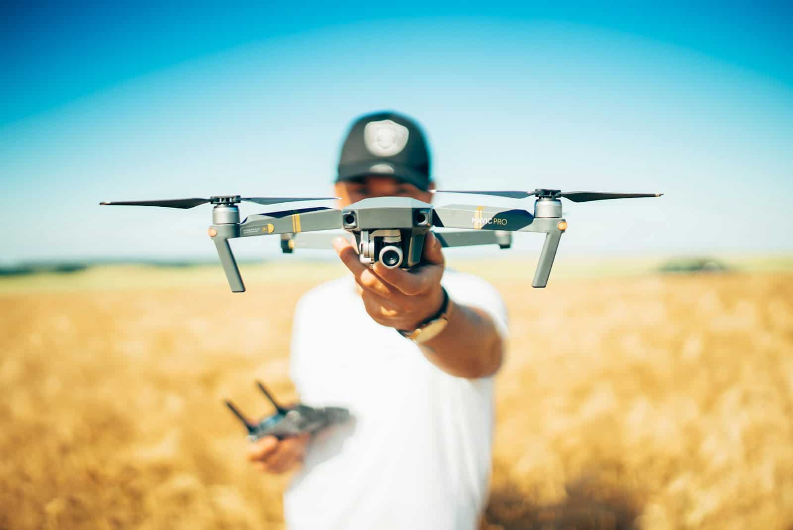 A man holding a small drone in a field.