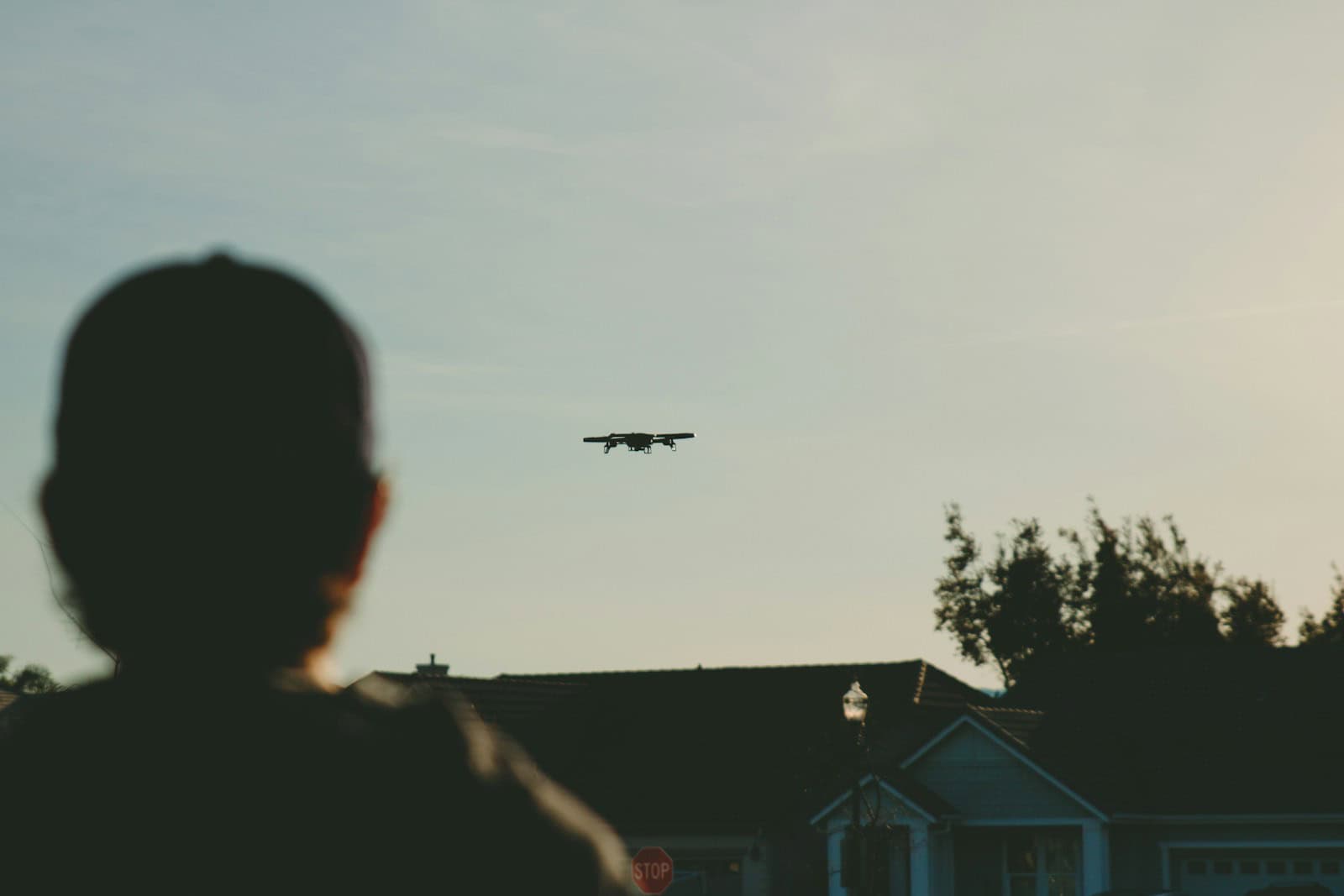 man standing while watching plane on sky during daytime