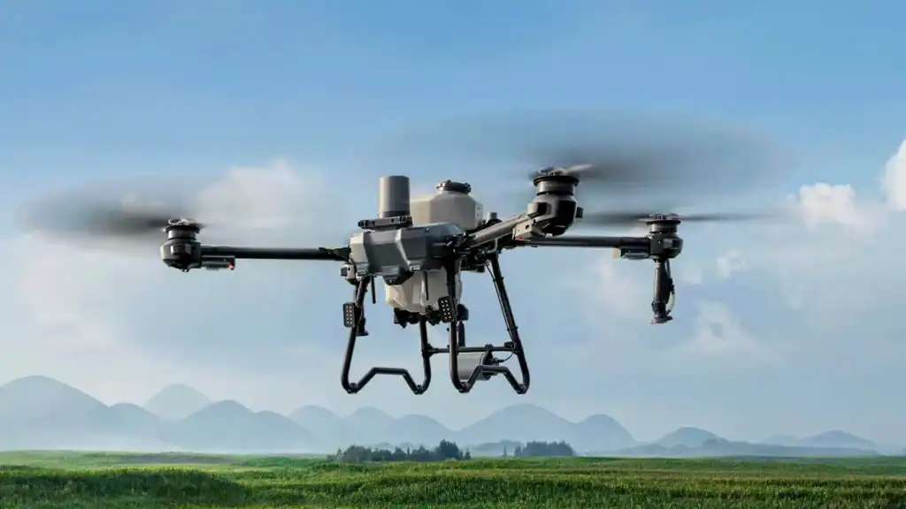 Dron DJI Agras 2025 nad polem z chmurami w tle.
