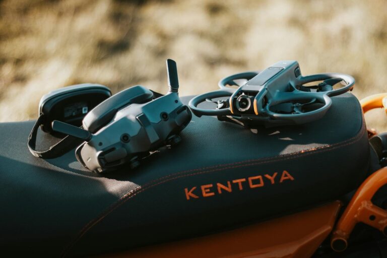 FPV drone and goggles placed on a motorcycle seat with 'Kentoya' visible, showcasing outdoor tech setup.