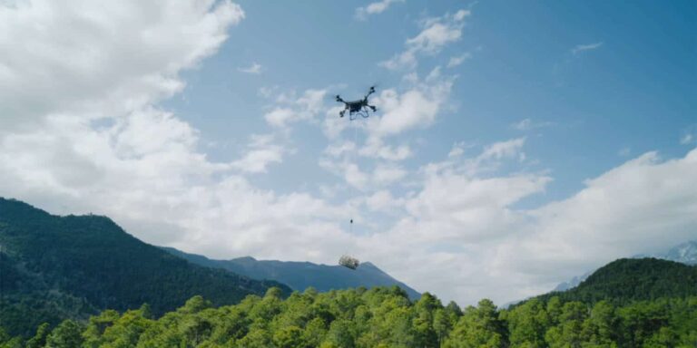 Dron z ciężkim ładunkiem, DJI FlyCart 200, w powietrzu nad górami, gotowy do transportu dużych ładun.